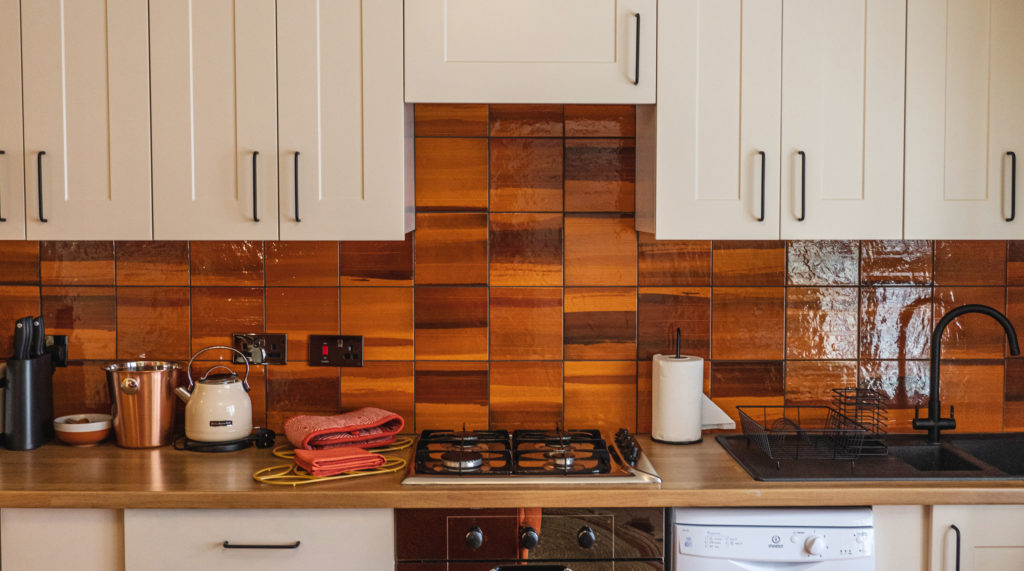 kitchen with orange and black tiles and kitchen appliances